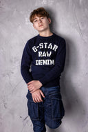 Model wearing navy stencil sweater and cargo jeans